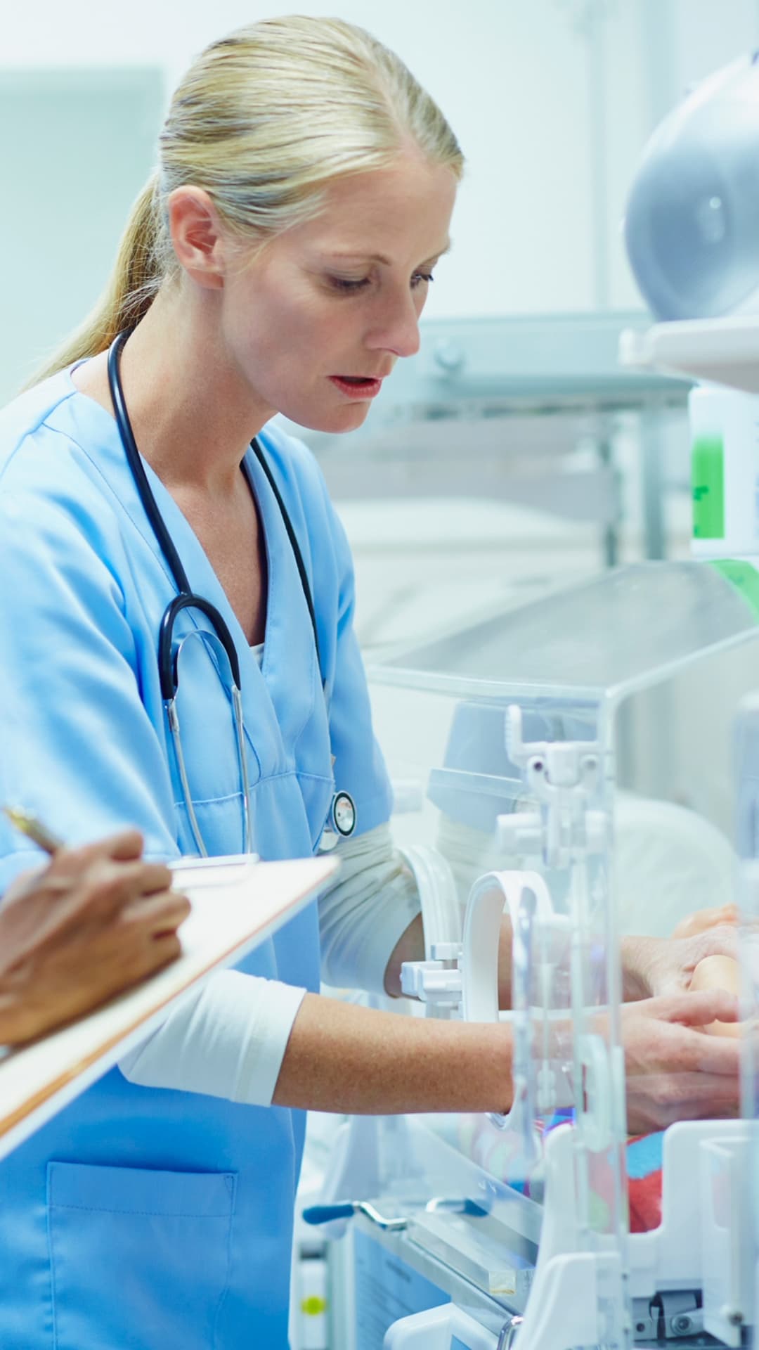 Sjuksköterska som arbetar vid en kuvös på en neonatalavdelning